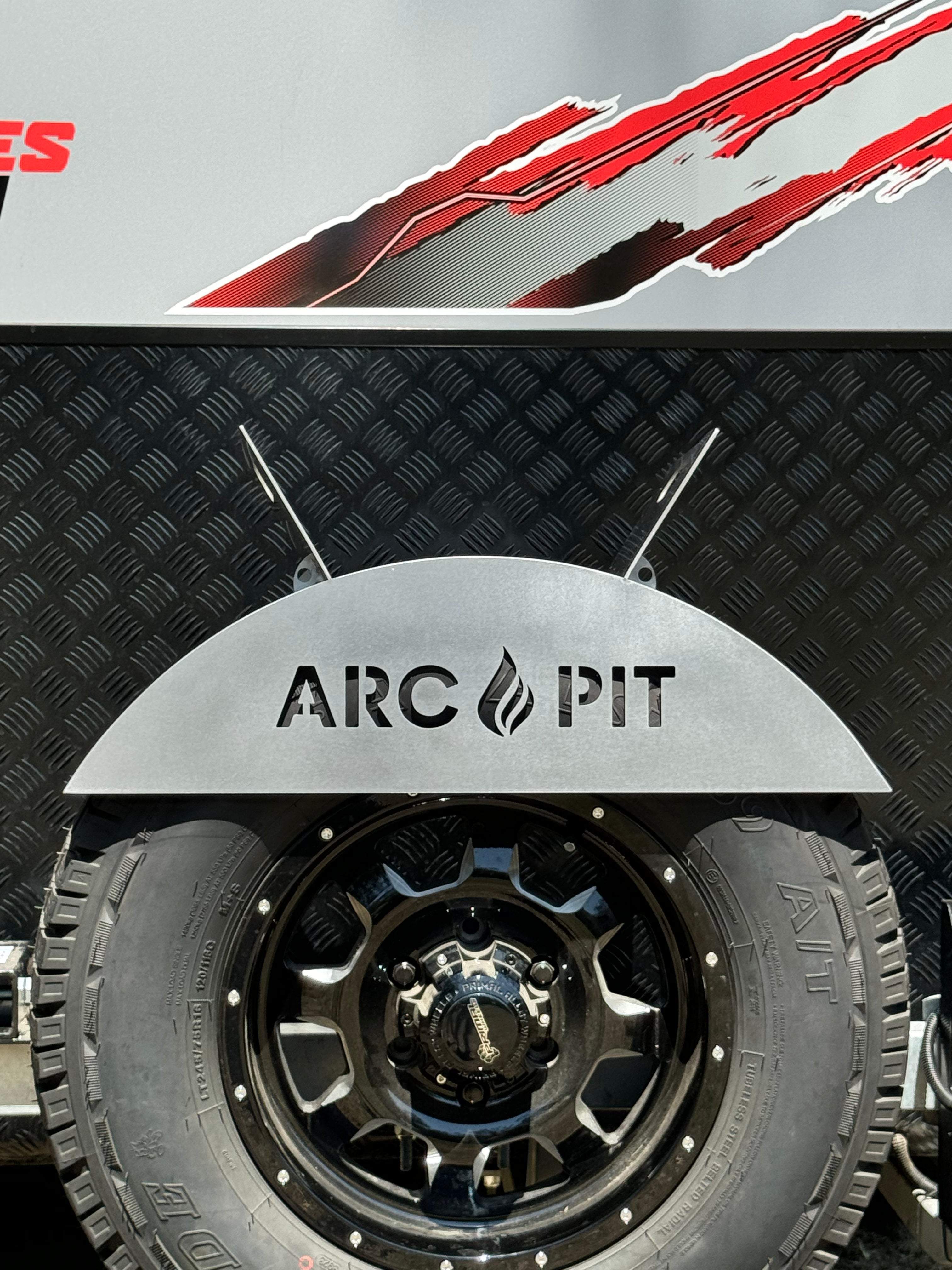 ArcPit portable fire pit stored securely on a 4WD spare tyre, ready for a campfire setup.